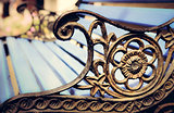 Detail of old park bench with ornaments, bokeh background