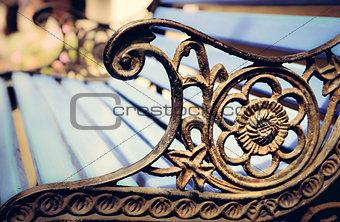 Detail of old park bench with ornaments, bokeh background