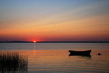 Lone rowboat in calm water at sunset