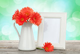 Orange gerbera flowers and photo frame on wooden table