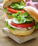 snack burger with fresh vegetables and ham on a wooden board