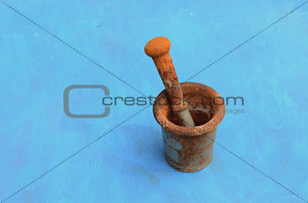 antique rusty iron mortar with pestle on blue background