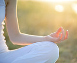 Young Beautiful Woman Practices Yoga on the Sunny Meadow