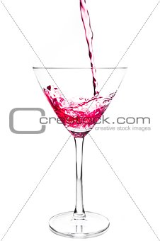 filling a glass with red cocktail and splashing