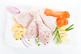 Chicken legs with vegetables on white tray.