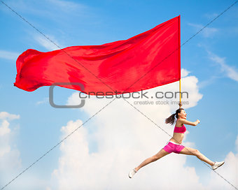 Beautiful Asian female jumping with big red flag 