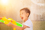happy little boy yelling and playing water guns in the park
