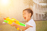 little boy shouting and playing water guns in the park