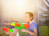 Cheerful girls playing water guns in the park