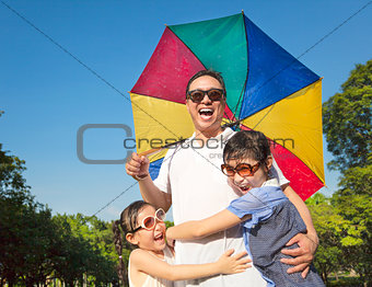 Father holding a colorful umbrella and hug two daughter