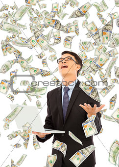 happy business man holding a laptop with money rain