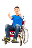 happy young man sitting on a wheelchair and thumb up