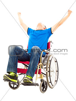 excited young man sitting on a wheelchair and raising hands