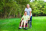 Asian senior woman sitting on a wheelchair with his husband