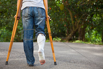 Young asian man on crutches with tree background