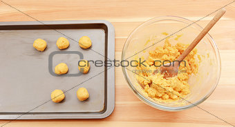 Adding balls of cookie dough to a baking sheet