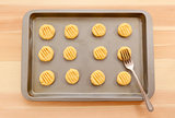 Flattening balls of biscuit dough on a tray