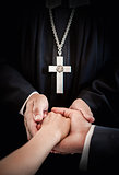 Priest holding bride's and groom's hands during wedding ceremony