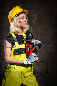 Attractive builder woman with a drill in her hands