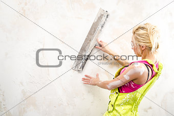 Female with putty knife working indoors
