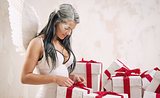 Young woman as angel with heap of gift boxes 
