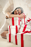 Beautiful young woman as angel with heap of gift boxes