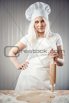Woman holding rolling pin wearing uniform posing indoors