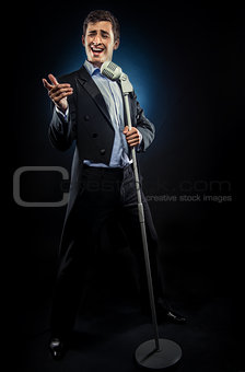 Man in elegant black jacket and blue shirt singing