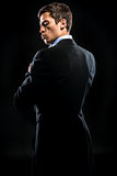 Man in elegant black suit posing over black background