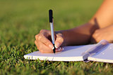 Close up of a woman hand writing on a notebook outdoor