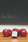 Apples with note on desk with blackboard in background 