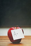  Red apple with note on desk with blackboard