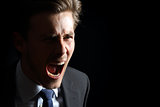 Angry businessman shouting isolated in black