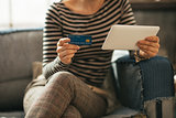 Closeup on young woman with credit card and tablet pc sitting on
