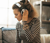 Young woman listening music in headphones in loft apartment