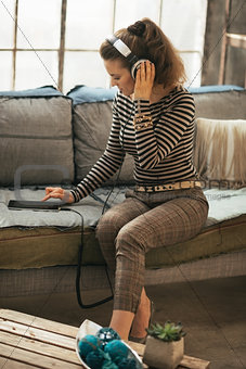 Young woman listening music in headphones in loft apartment