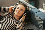 Portrait of young woman listening music in headphones while layi