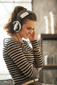 Portrait of happy young woman listening music in headphones in l
