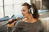 Portrait of young woman singing with microphone in loft apartmen