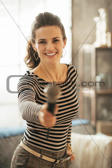 Happy young woman stretching microphone in camera