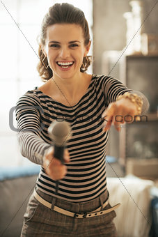 Happy young woman stretching microphone in camera and pointing