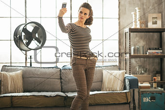 Young woman taking self photo in loft apartment