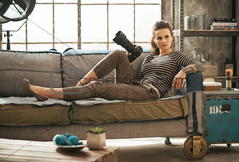 Happy young woman laying on couch in loft apartment with modern 