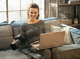 Young woman with modern dslr photo camera using laptop in loft a