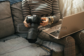 Closeup on young woman with laptop using modern dslr photo camer