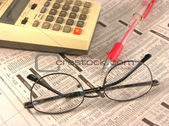 Pen, glasses and calculator on newspaper