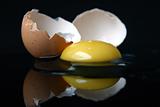 Still-life with a broken egg, on black background with reflection