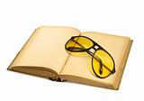open book with yellow sunglasses on white 