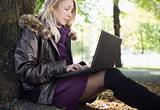 Young blond woman using computer outdoors