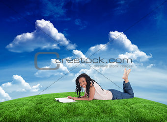 Composite image of a woman lying on the floor smiling at the camera with a magazine in front of her